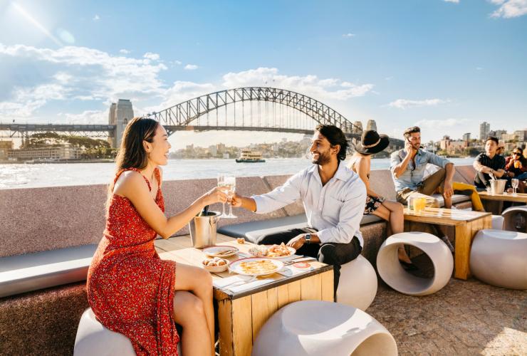 Sepasang kekasih menikmati makanan dan minuman dengan pemandangan pelabuhan di Opera Bar, Sydney, New South Wales © Destination NSW