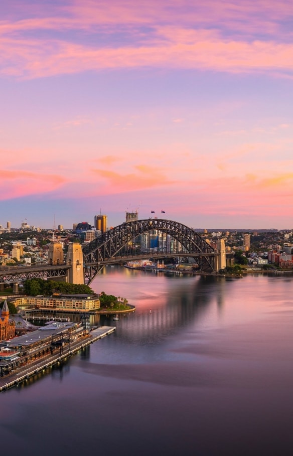 Luftaufnahme von Sydney Harbour in Sydney, in dem sich die Blau-, Rosa- und Goldtöne des Sonnenuntergangs spiegeln, New South Wales © Destination NSW