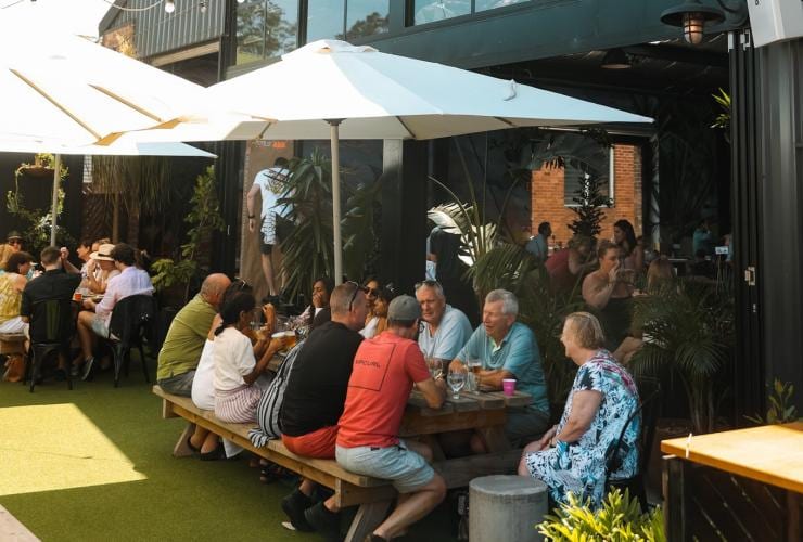 Groups of people seated at outdoor tables beneath umbrellas while drinking beer at One Drop Brewing, Botany, Sydney, New South Wales © One Drop Brewing Co