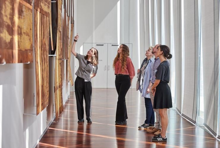 A group of people standing in a light-filled room as a tour guide points toward art hanging on a wall at the Art Gallery of New South Wales, Sydney, New South Wales © Art Gallery of New South Wales