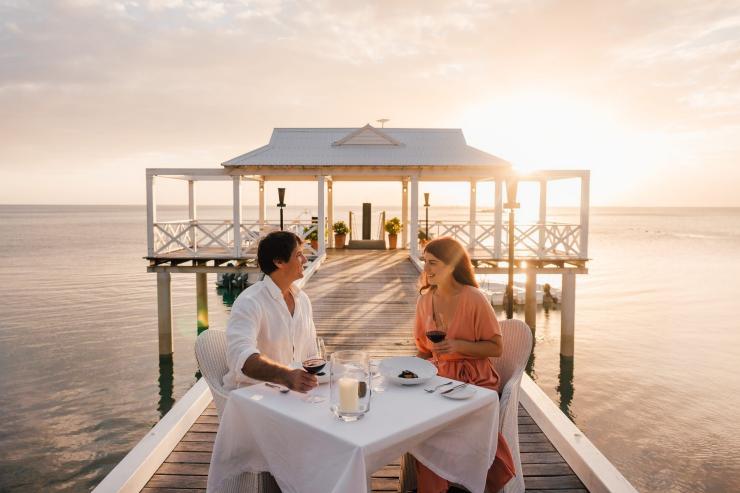 A couple dining on a pier at sunset at Orpheus Island Lodge, Great Barrier Reef, Queensland © Tourism and Events Queensland