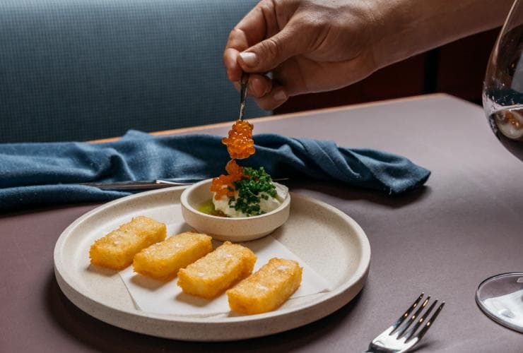 Close up of a hand placing orange fish roe on a carefully plated dish at Fugazzi Bar & Dining Room, Adelaide, South Australia © Julian Cebo