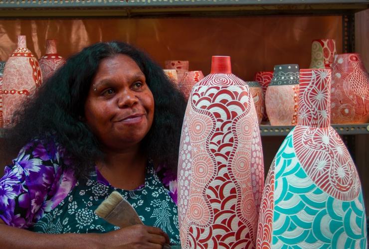 An Aboriginal artist seated beside ceramic artworks at Ernabella Art, Longitude 131, Uluru, Northern Territory © Longitude 131