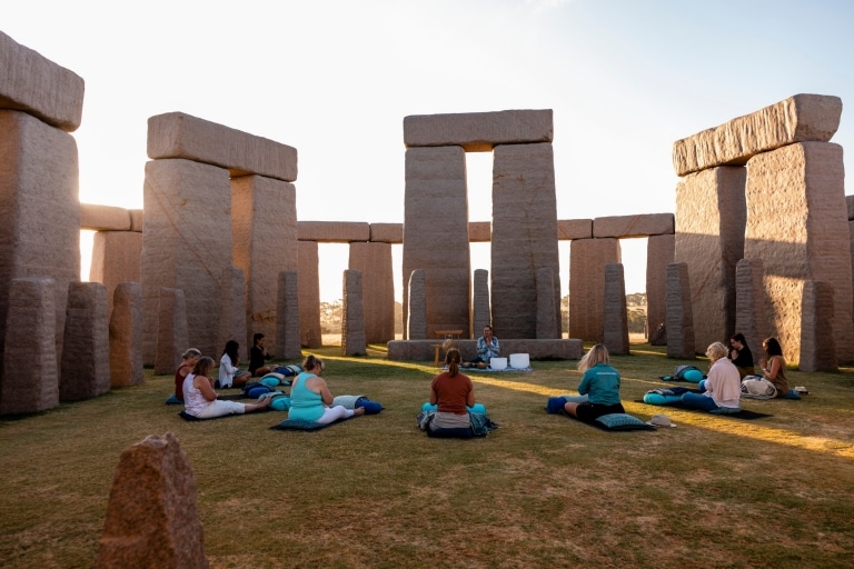 Un groupe de femmes assises en cercle sur l'herbe, entourées de grands rochers gris à Esperance, Australie Occidentale © Tourism Australia