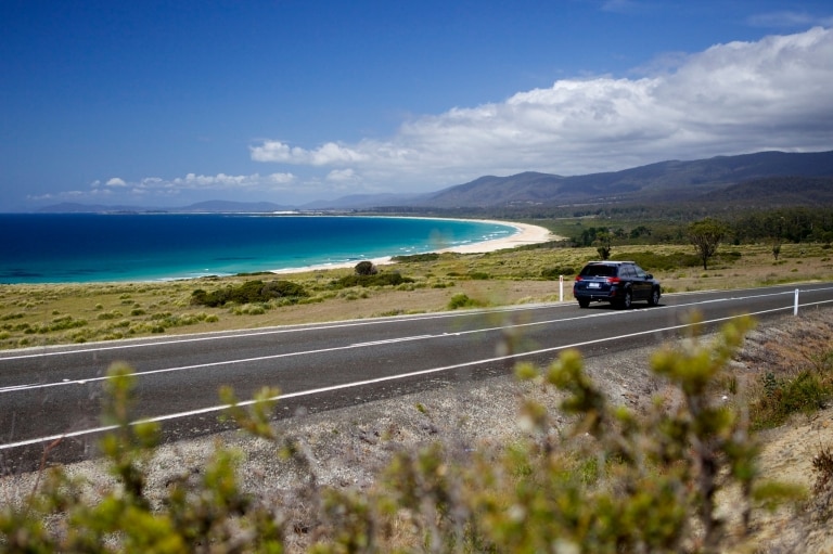 Mobil melaju di jalan di samping samudra di Lagoons Beach Conservation Area © Pete Harmsen/Tourism Tasmania