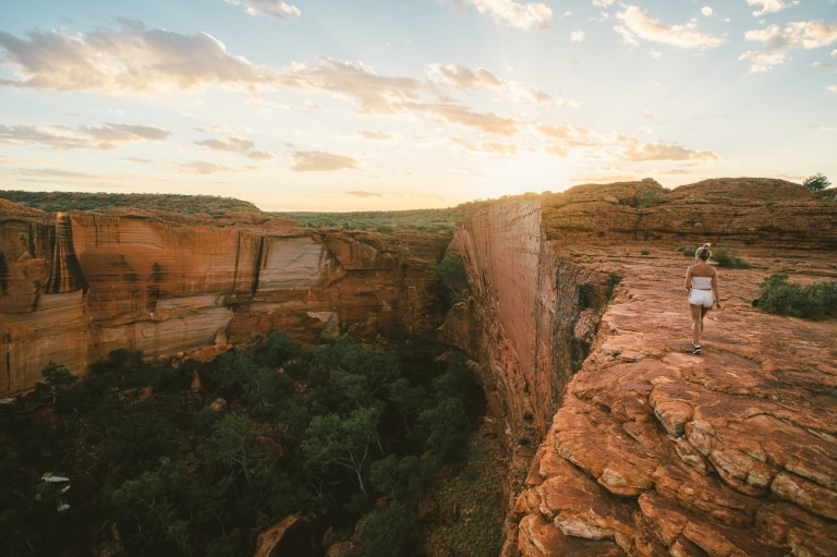  Seorang perempuan sedang berjalan di atas Kings Canyon saat matahari terbit © Tourism NT/Mitchell Cox 2017