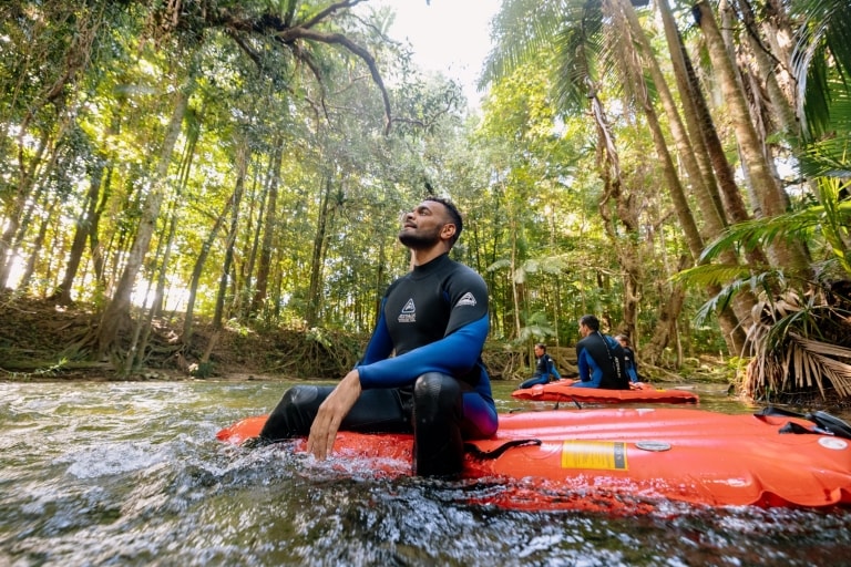 데인트리 열대우림에서 진행되는 백 컨트리 블리스 어드벤처 중 한 남자가 강물 위에 떠 있는 래프트 위에 앉아 녹색의 열대우림 캐노피를 올려다보고 있는 모습, 퀸즐랜드 © 호주정부관광청