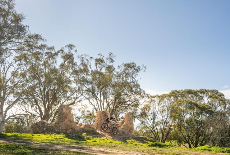 Eine Person auf einem Mountainbike springt in der Luft zwischen einem Haufen Ziegelsteine hindurch, Melrose, Flinders Ranges und das Outback, Südaustralien © Heidi Who Photos
