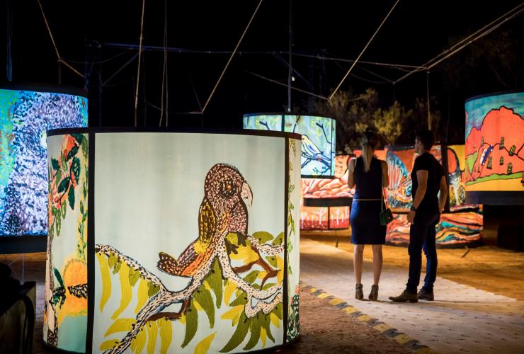Zwei Personen stehen inmitten eines Kaleidoskops bunter Kunstinstallationen mit Bildern einheimischer Vögel, Parrtjima – A Festival in Light, Alice Springs, Northern Territory © Tourism NT/James Horan