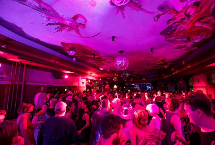 Ein Raum voller Menschen, die unter einem bemalten Dach unter rosa und lila Lichtern tanzen, The Imperial Hotel, Erskineville, Sydney, New South Wales © Destination NSW