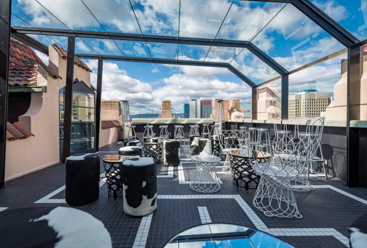 Eine stilvolle Rooftop-Bar mit Glasvordach und Blick auf die Gebäude der Stadt, Hennessy Bar, Adelaide, Südaustralien © Tourism Australia