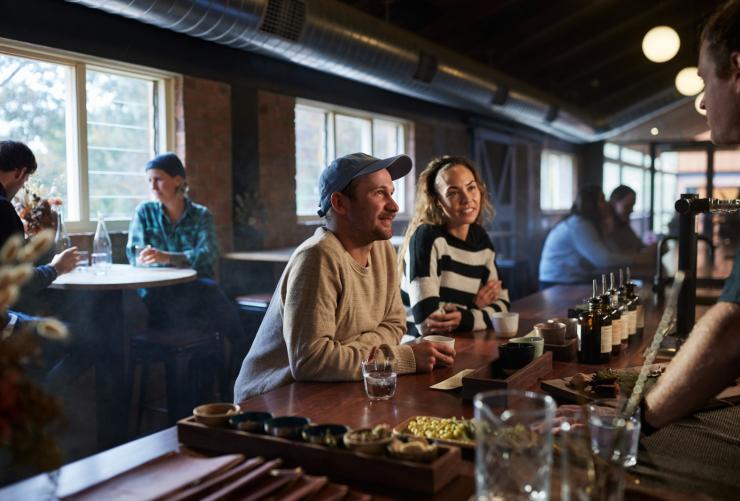 Gäste sitzen an einer Bar, probieren Spirituosen und unterhalten sich mit dem Barkeeper, Applewood Distillery, Adelaide Hills, Südaustralien © South Australian Tourism Commission