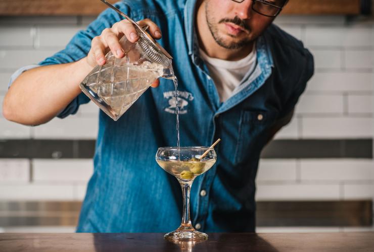Nahaufnahme eines Barkeepers, der einen Martini mit Oliven zubereitet, Manly Spirits Co., Manly, New South Wales © Alana Dimou