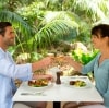 Ein Paar stößt an einem sonnigen Tag bei einem Mittagessen im Freien mit Wein an, umgeben von grünen Bäumen und Pflanzen, Pinetrees Lodge, Lord Howe Island, New South Wales © Destination NSW