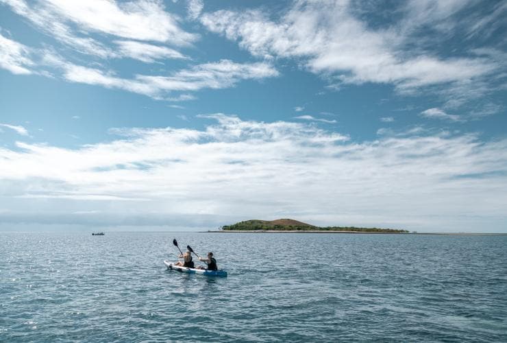 Zwei Personen fahren Kajak im blauen Ozean, mit einer Insel in der Ferne, Camp Island Lodge, Whitsundays, Queensland © Camp Island Lodge