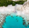 Luftaufnahme einer Cabana am Ende eines Stegs, der sich über weißen Sand in klares blaues Wasser erstreckt, aus dem Felsbrocken ragen, Haggerstone Island, Great Barrier Reef, Queensland © Tourism and Events Queensland