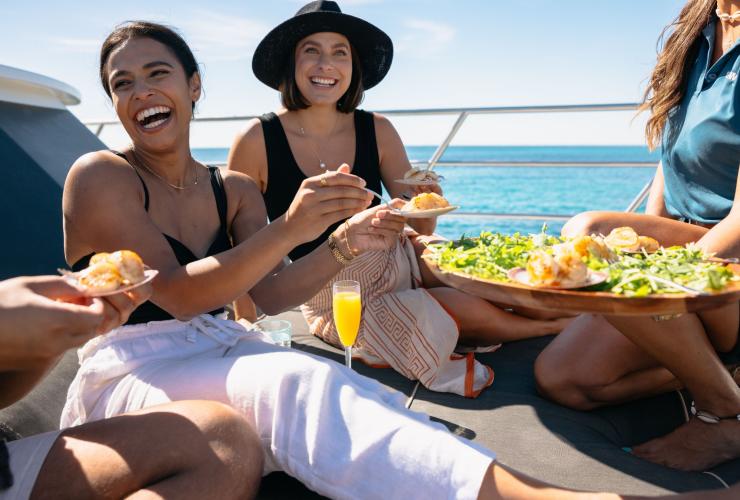 A group of friends laughs as they enjoy a seafood platter with Rottnest Cruises, Rottnest Island, Western Australia © Tourism Australia