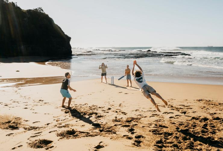 Four friends play cricket on the sand at Coledale Beach, Thirroul, New South Wales © Destination NSW