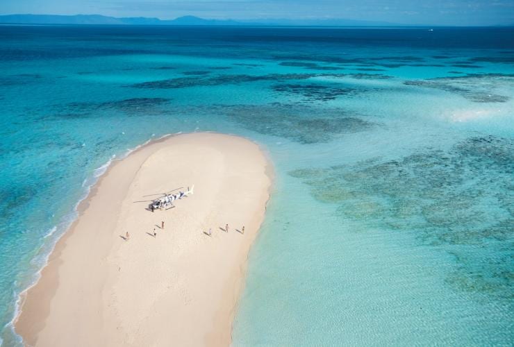 Aerial view over Vlasoff Cay with a helicopter and a group of people on the white sandy stretch surrounded by the Great Barrier Reef, Queensland © Tourism and Events Queensland