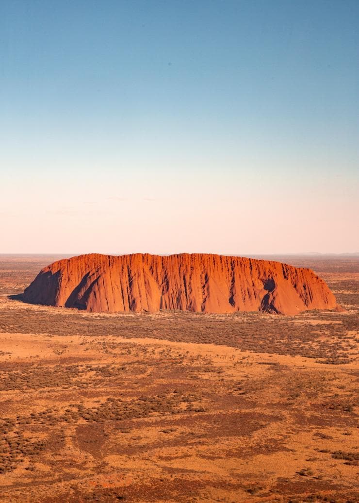 Aerial view over the red monolith of Uluru and surrounding grassy plains in Uluru-Kata Tjuta National Park, Northern Territory © Tourism Australia/Nicholas Kavo