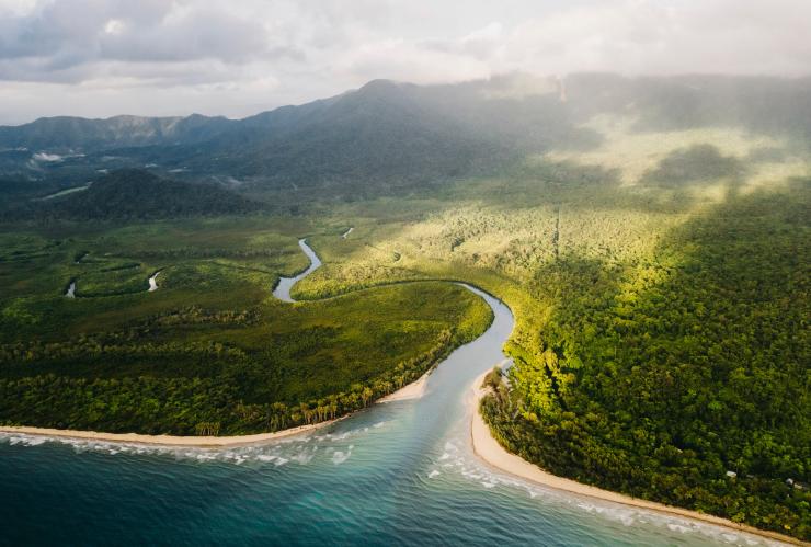 Aerial view of the white sand and clear blue water of Thornton Beach leading into the green, mountainous expanse of the Daintree Rainforest, Queensland © Tourism Tropical North Queensland