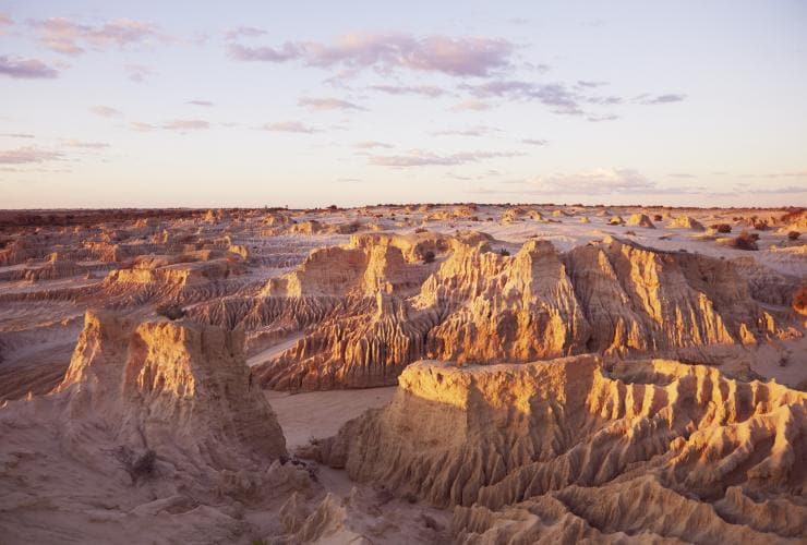 An off-white, rocky expanse of clay and sand dunes at Mungo National Park during sunset, New South Wales © Destination NSW