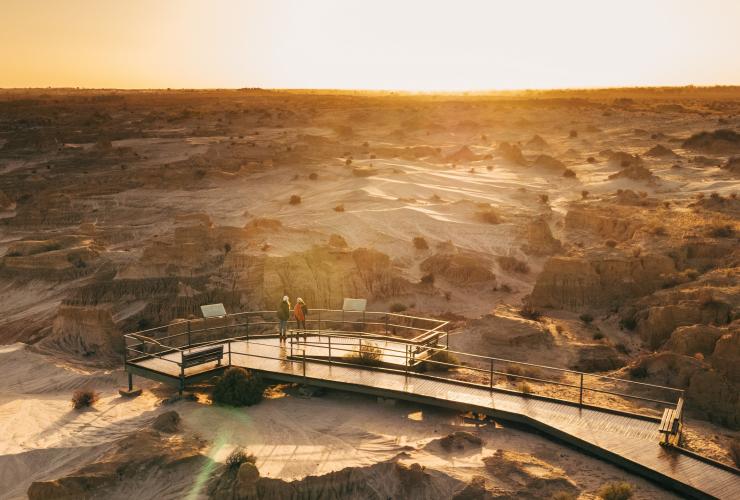 Aerial view over two people standing at Red Top Lookout overlooking the sand and clay expanse of Mungo National Park during sunset, New South Wales © Melissa Findley