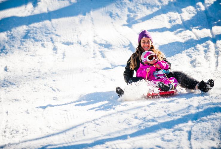 Woman and child smiling while sledding down a snowy hill on a toboggan at Corin Forest, Paddys River, Australian Capital Territory ©  Damian Breach Photography