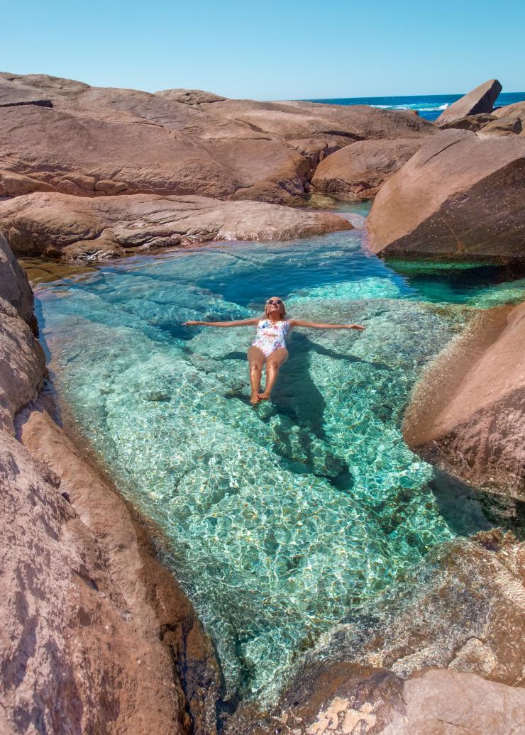 A woman floating on her back in a clear blue rock pool at Boranup Beach, Margaret River, Western Australia © Tourism Western Australia/@helen_jannesonbense