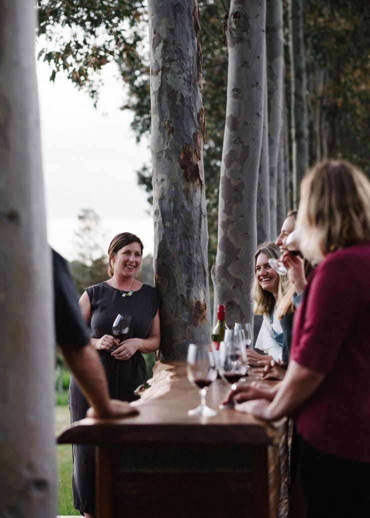 A group of people standing outside surrounded by trees around a table with glasses of red wine at Glenarty Road, Margaret River, Western Australia © Emma Pegram