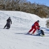 Two people with limited mobility adaptive skiing with instructors down a snow-covered mountain in Thredbo, Snowy Mountains, New South Wales © Tourism Australia