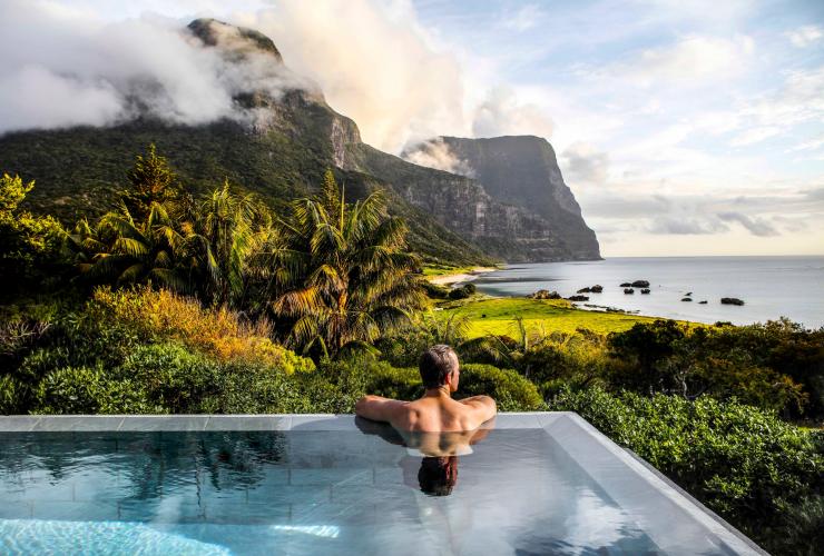 A man swimming in a pool overlooking rainforest, mountains and coast from Capella Lodge, Lord Howe Island, New South Wales © Baillie Lodges
