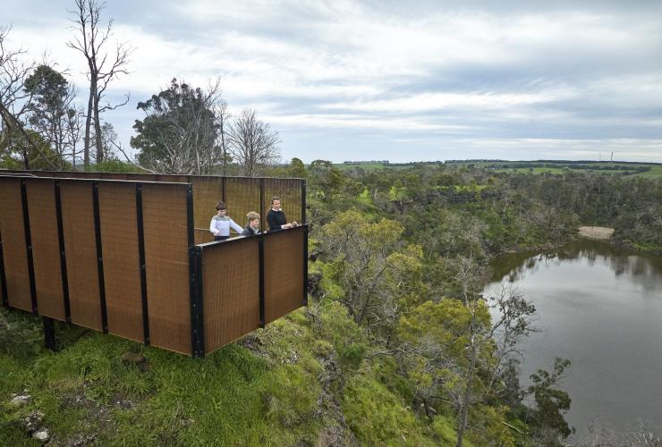 A family standing at a lookout overlooking a wetland during a tour with Budj Bim Cultural Landscape Tourism, Great Ocean Road, Victoria © Tourism Australia