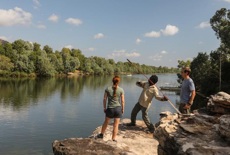 Visitors with an Aboriginal guide demonstrating spear throwing on the banks of a river during a Guluyambi Cultural Cruise, Kakadu National Park, Northern Territory © Tourism NT/James Fisher