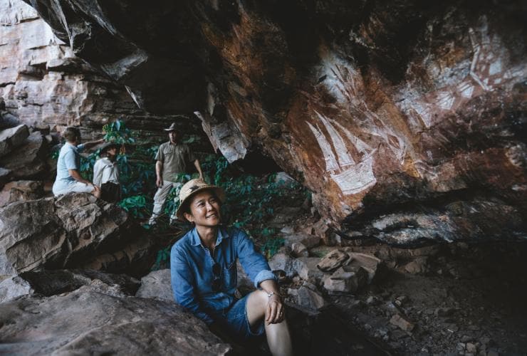 A group of people talking and admiring Aboriginal rock art during a tour with Kakadu Cultural Tours, Kakadu National Park, Northern Territory © Tourism Australia