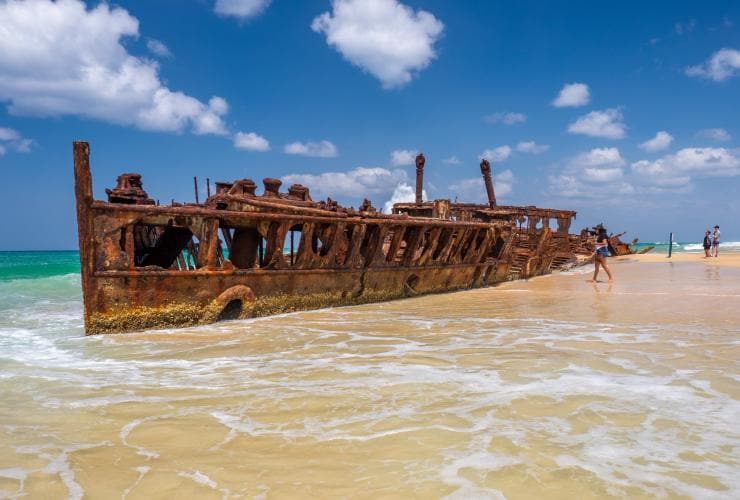 People exploring the ruins of Mehano Shipwreck in the shallow waters of the K’gari coastline in Queensland © Tourism Australia