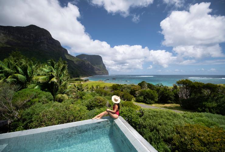 A woman sitting on the corner of a pool at Capella Lodge overlooking the greenery and coastline of Lord Howe Island, New South Wales © Tom Archer