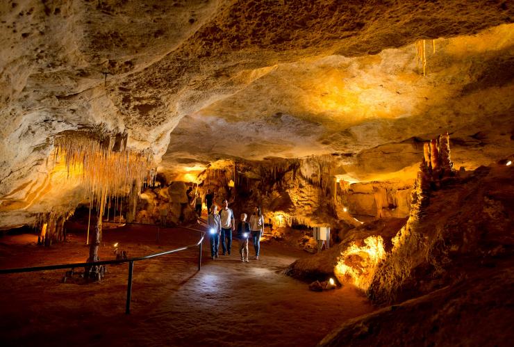 A family walking through the underground formations of Naracoorte Caves National Park while holding torches, Naracoorte, South Australia © South Australian Tourism Commission/Adam Bruzzone