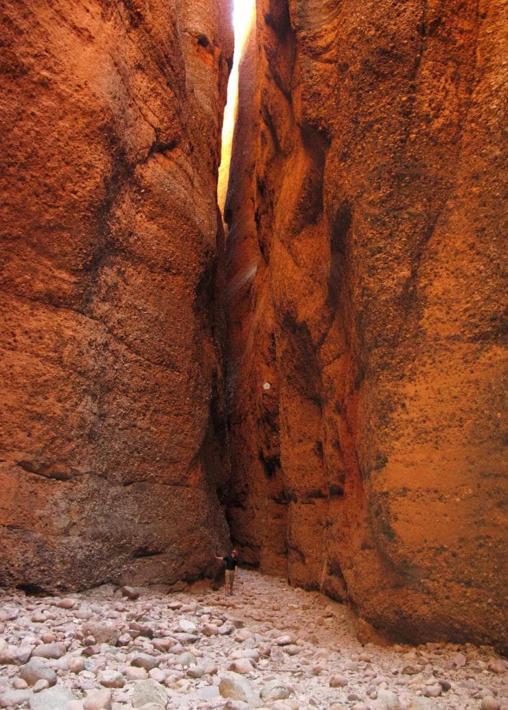 A man standing beneath the towering red rock walls of Echidna Chasm, Purnululu National Park, Western Australia © Tourism Australia