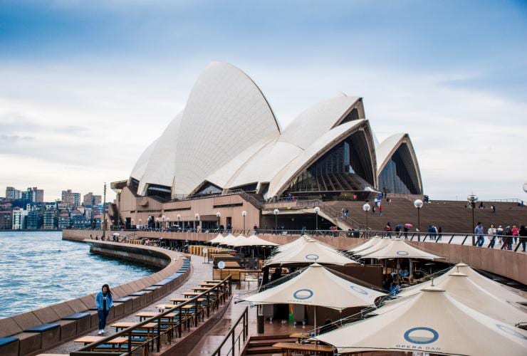 Looking over umbrellas and tables toward the sails and structure of Sydney Opera House, Sydney, New South Wales © Susan Kuriakose/Unsplash