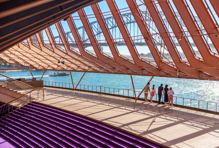 A group of visitors immerse themselves in an architectural tour of the Sydney Opera House, standing at its edge overlooking Sydney Harbour in Sydney, New South Wales © Tourism Australia