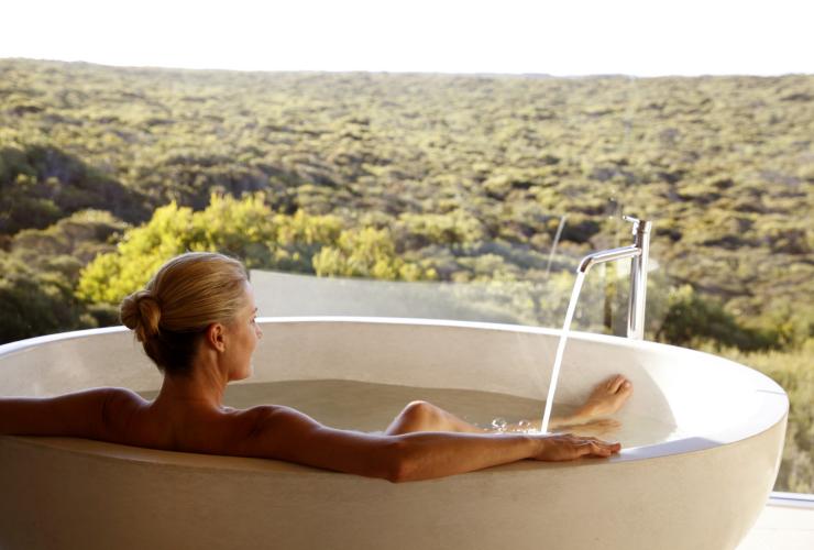 A person relaxing in a large bath while overlooking bushland through floor to ceiling windows at Southern Ocean Lodge, Kangaroo Island, South Australia © Southern Ocean Lodge