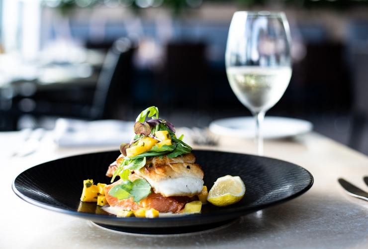 A barramundi dish with lemon beside a glass of white wine at Dundee’s Waterfront Restaurant, Cairns, Queensland © Alexandra Gow