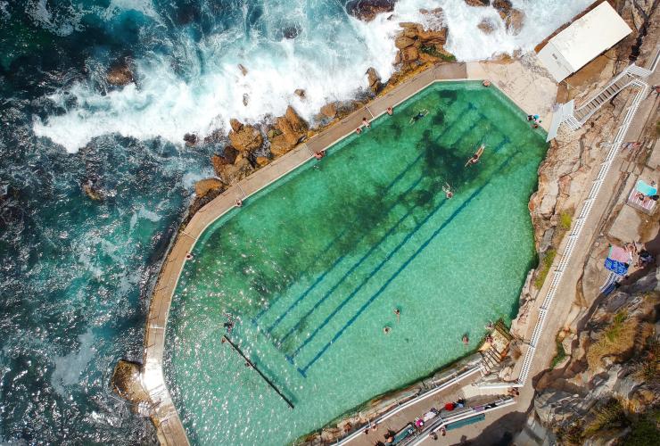 Aerial view over people swimming at Bronte Baths with ocean waves crashing around its edge at Bronte Beach, Sydney, New South Wales © Ashlea Wheeler