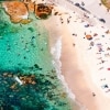 Aerial view of people laying on white sand and swimming in turquoise water at Bronte Beach, Sydney, New South Wales © Tourism Australia