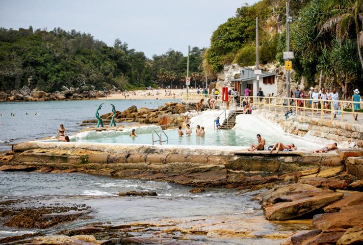 A crowd of people swimming, walking and laying around the Fairy Bower Ocean Pool, Manly, Sydney, New South Wales © Destination NSW