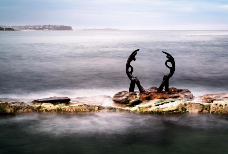 Close up of a rustic sculpture embedded on the edge of Fairy Bower Ocean Pool with the ocean in the background in Manly, New South Wales © James Vodicka