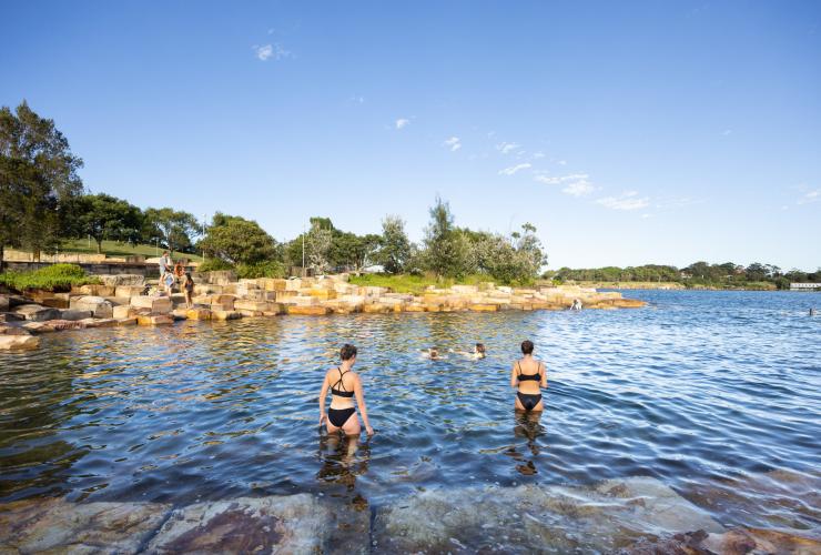 People standing and swimming in the sheltered waters of Marrinawi Cove during sunset at Barangaroo Reserve, Sydney, New South Wales © Images for Business