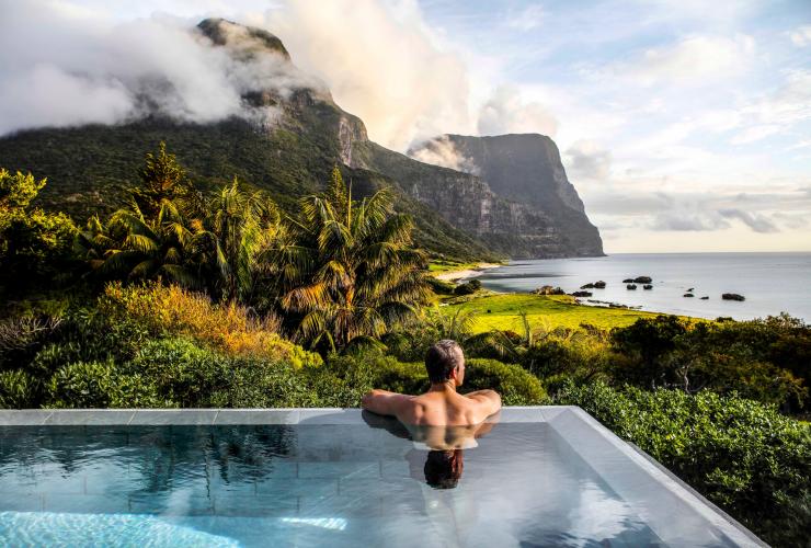 A man looks out into a lush green seaside landscape from an infinity pool at Capella Lodge, Lord Howe Island, New South Waless © Baillie Lodges