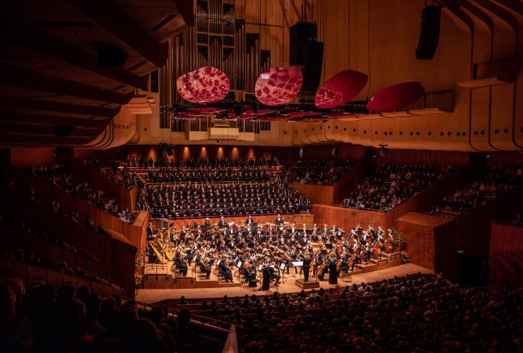 Plan large du Sydney Symphony Orchestra installé en demi-cercle et en pleine représentation devant un public nombreux assis à l'Opéra de Sydney, Sydney, Nouvelle-Galles du Sud © Daniel Boud